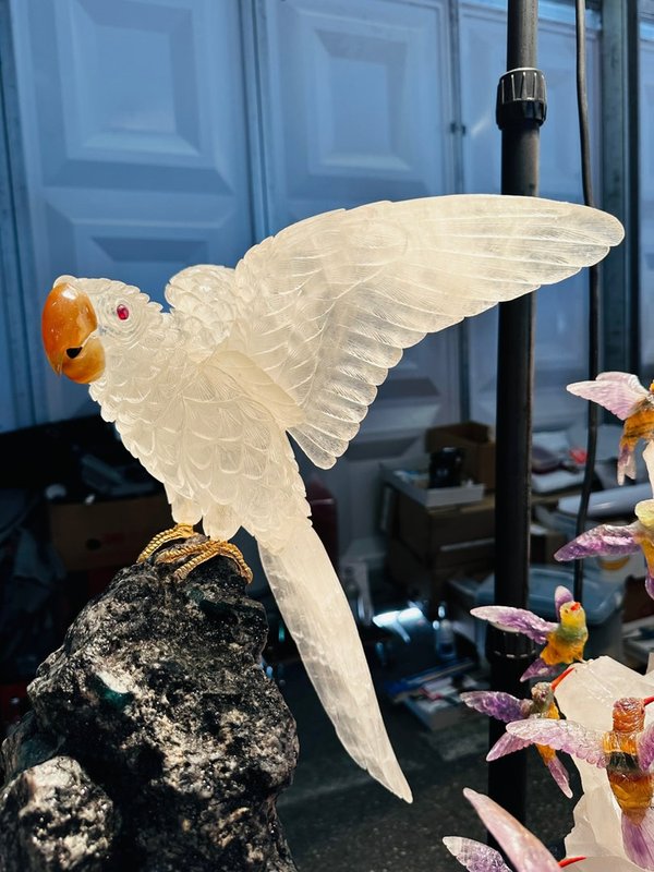 Large pair of parrots made of rock crystal on an emerald natural stone